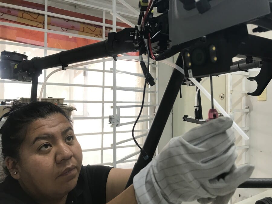Especialista realizando servicio de reparación de drones, ajustando el sistema de aspersión de un dron agrícola DJI con precisión técnica.