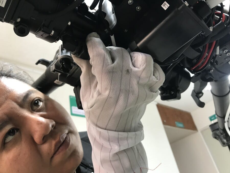 fotografia de mujer arreglando un dron usando guantes y ajustando piezas