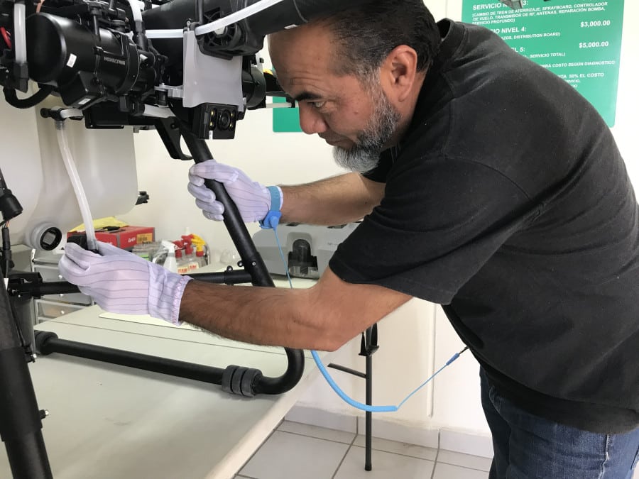 Técnico especializado realizando servicio de reparación de drones DJI, ajustando componentes con precisión en taller certificado.