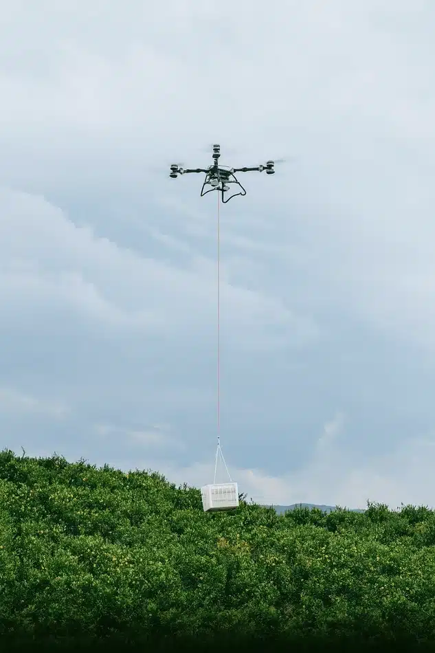 dji agras t100 llevando una carga sobre unos arboles