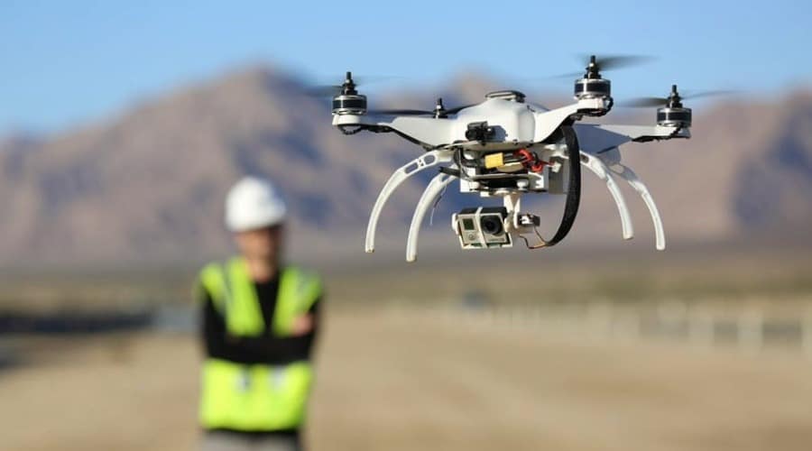 persona con chaleco de seguridad controlando dron para topografia en campo